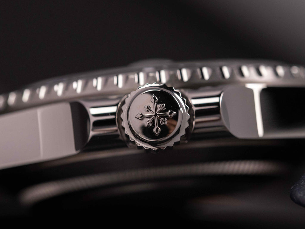 Close-up of a silver watch with a detailed emblem on a dark background